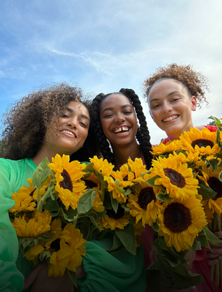 Ein scharfes und lebendiges Selfie von drei Personen mit Blumen.